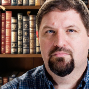 A man in a suit and tie stands confidently at a podium